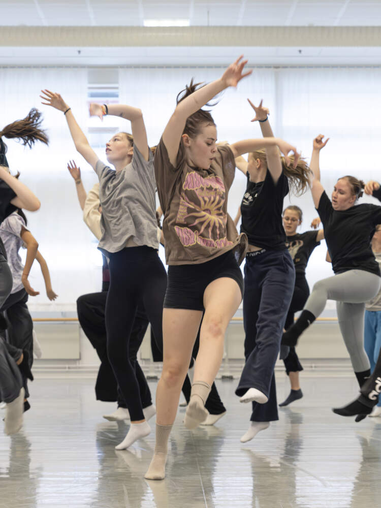 En grupp unga människor dansar energetiskt i en dansstudio.