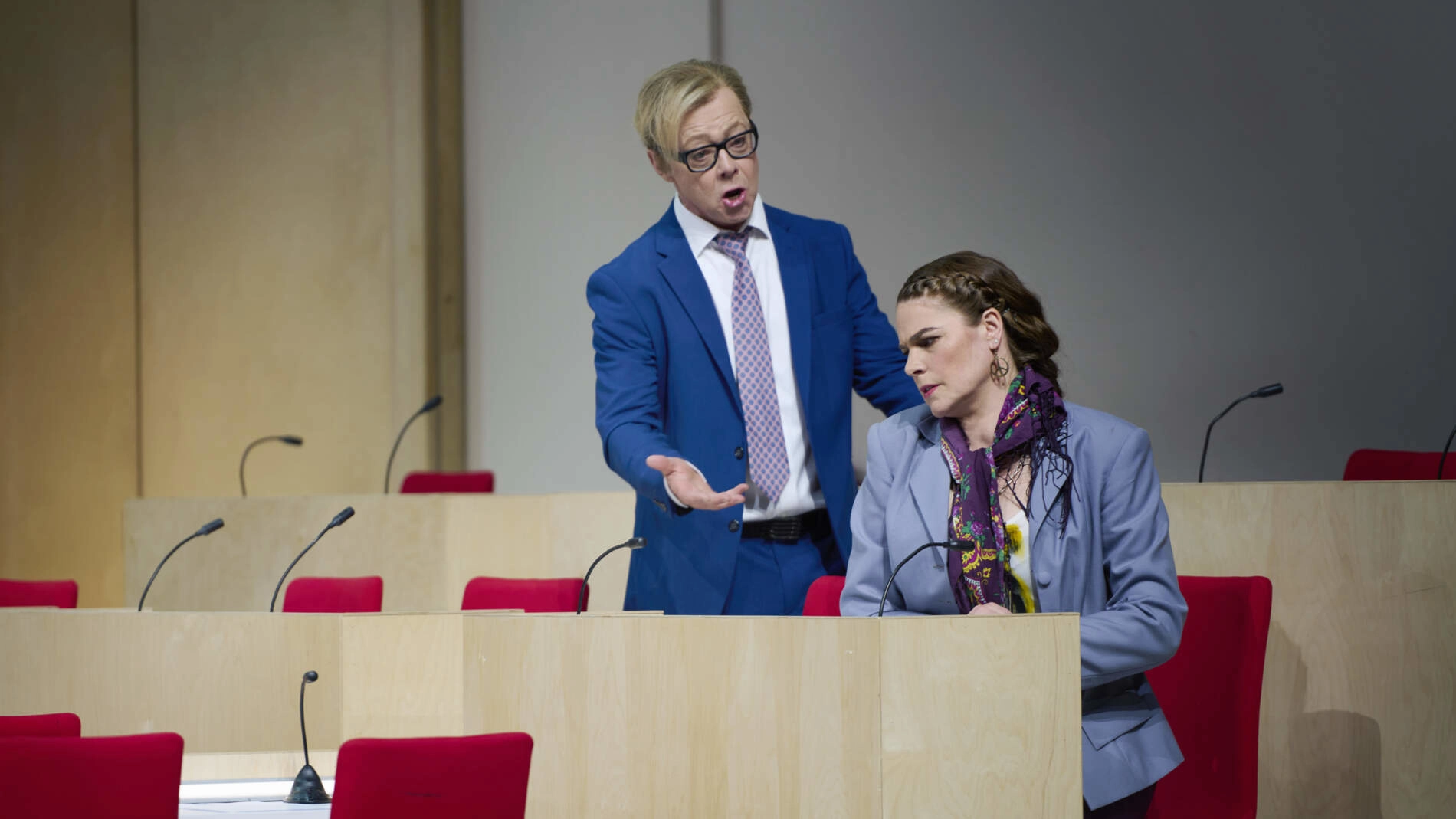 Ismael i kostym och slips står bakom Fenena och sjunger. Hon sitter på en stol i en politisk kammare med stolar i rader.